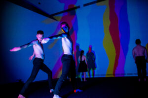 Michael Noble poses while colourful shadows bounce off the wall.