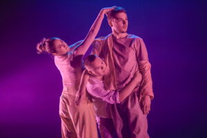 Dancers Madalene Macera, Charlie Wilkins, Bhodi Hudson in pink all in phases of touch.
