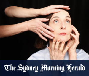 Michelle Ryan touching her face with her two hands while two other hands touch her face from someone you can't see.